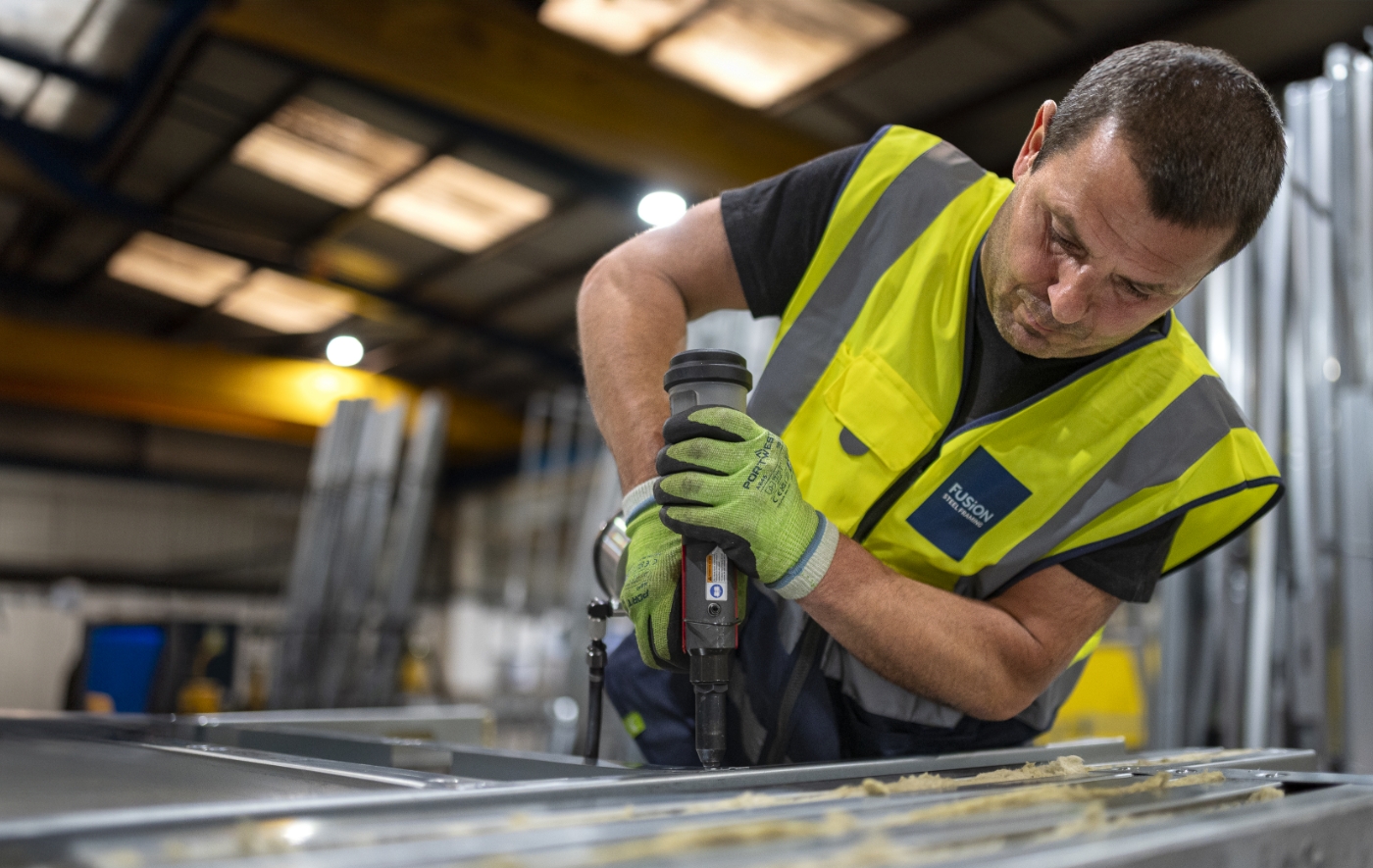 A Fusion employee constructing  a load-bearing wall in the factory.